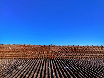 Low angle view of roof tiles against clear blue sky