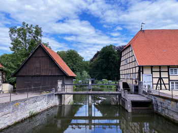 House by lake and building against sky