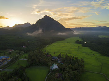 Scenic view of agricultural field against sky at sunset