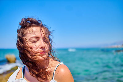 Young woman with brown hair at beach against sky