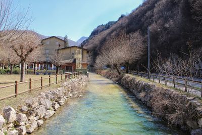 River amidst houses and trees against sky