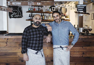 Portrait of male partners standing at bar counter