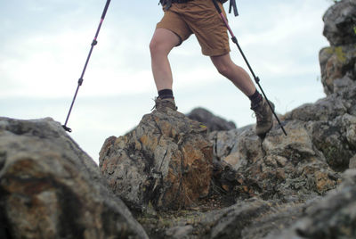 Low section of hiker on rocky mountain against sky