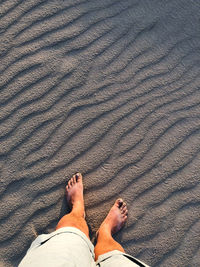 Low section of man standing on sand