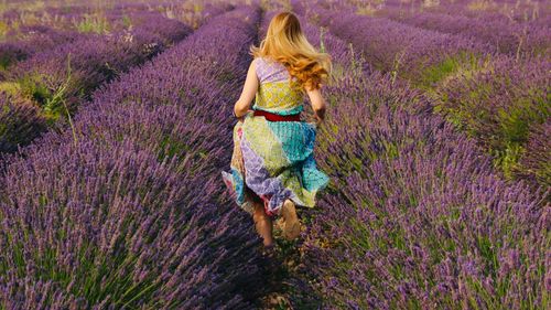 Full length rear view of woman running by plants