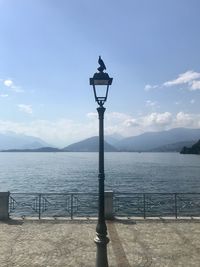 Street light by lake against sky