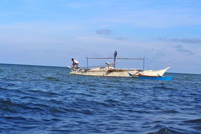 Fishing boat in sea against sky