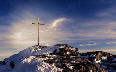 Windmill on mountain against sky during winter
