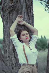 Full length of young woman standing on tree trunk