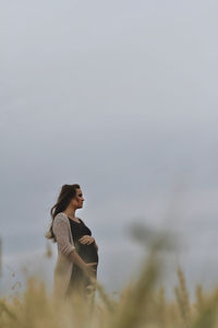 Low angle view of pregnant woman standing against clear sky