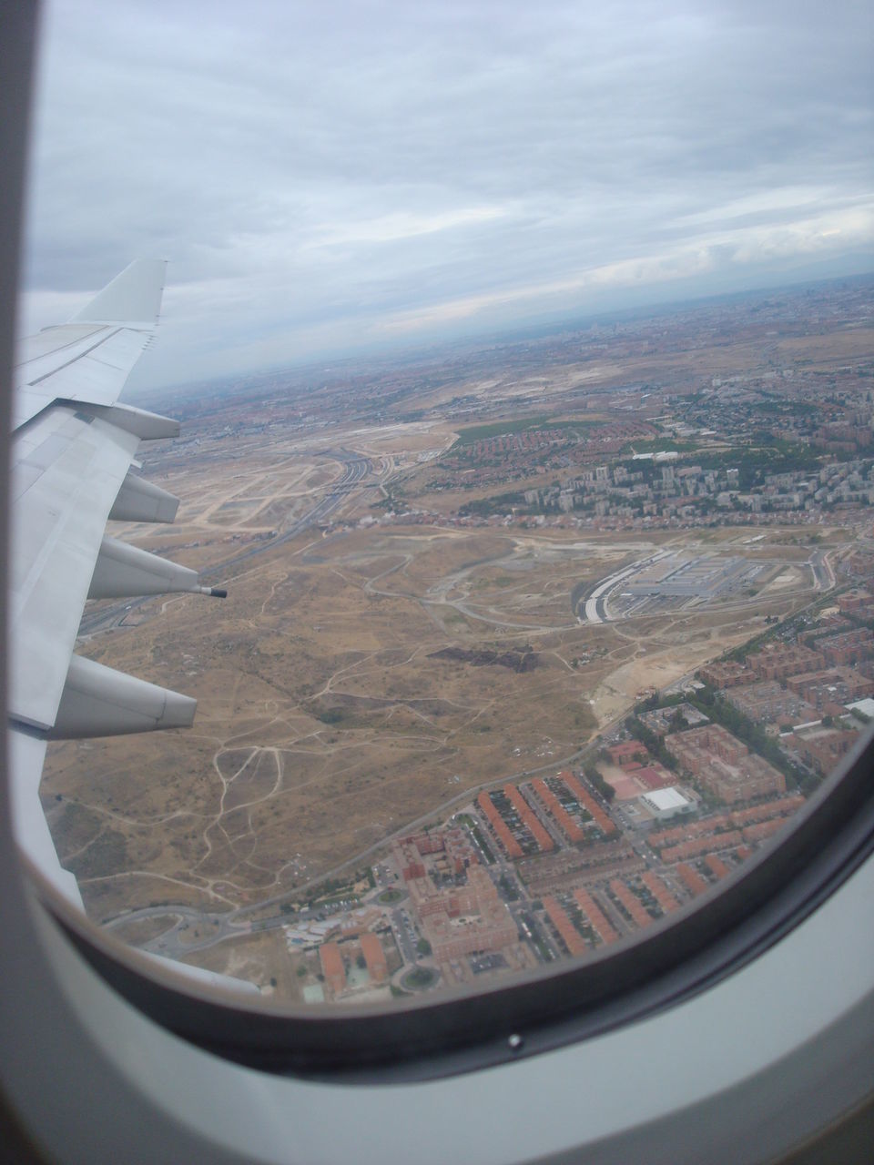 AERIAL VIEW OF LANDSCAPE AGAINST SKY SEEN THROUGH AIRPLANE WINDOW