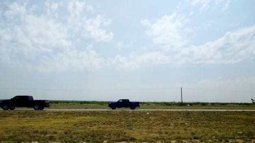 Cars on field against sky