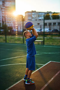 Sports and basketball. boy in a blue tracksuit throwing a basketball ball into the hoop 