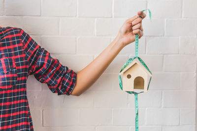 Midsection of woman house with tape measure against wall