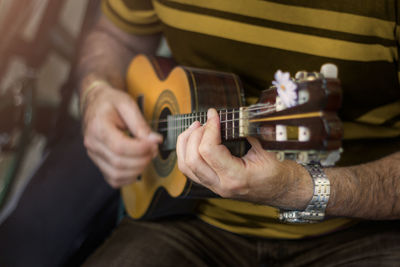 Midsection of man playing ukulele