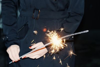 Midsection of woman holding lit sparkler