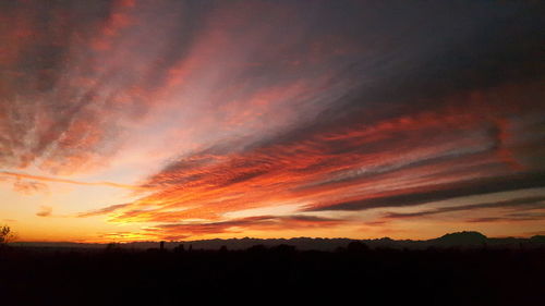 Silhouette landscape against dramatic sky during sunset