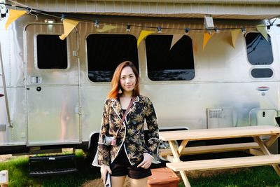 Portrait of young woman standing by motor home