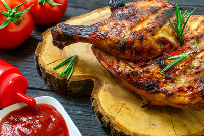 Baked part of tasty chicken, with golden brown crust, cooked on grill or barbecue on dark table.