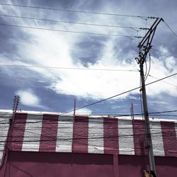 Low angle view of power lines against cloudy sky