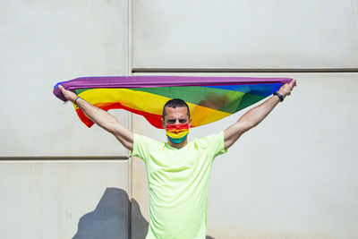 Full length of young man with arms raised against wall