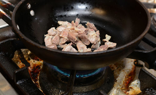 High angle view of meat roasting in pan on gas stove burner