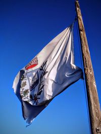 Low angle view of flag against clear blue sky