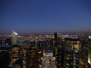 Illuminated buildings in city against clear sky at night