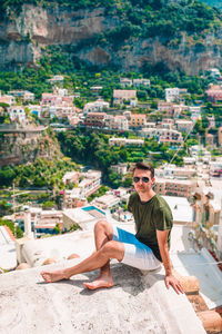 Portrait of young man sitting on built structure