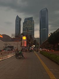 Illuminated buildings by road against sky in city