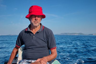 Man standing on boat in sea against blue sky