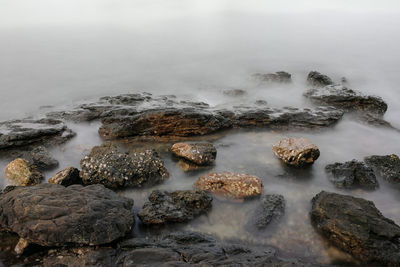 Scenic view of rocks in sea during foggy weather