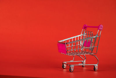 Red shopping cart against orange wall