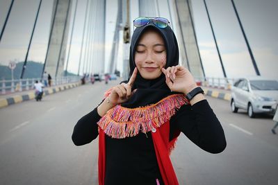 Young woman standing against car in city