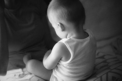 Baby boy sitting on bed in the evening