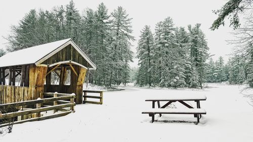 Gazebo on snow covered landscape against sky