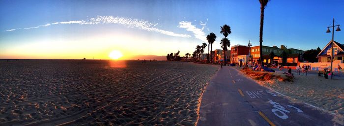 People on road in city against sky during sunset