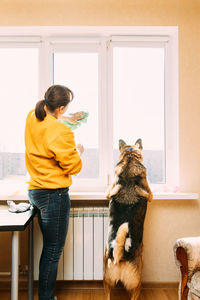 Rear view of woman cleaning window at home