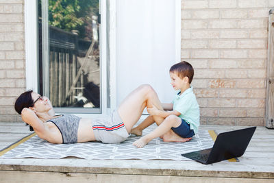 Family sport activity. middle age caucasian mother with toddler doing sit-ups exercices on backyard. 