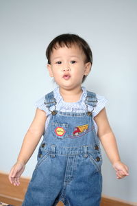 Portrait of cute girl standing against gray background