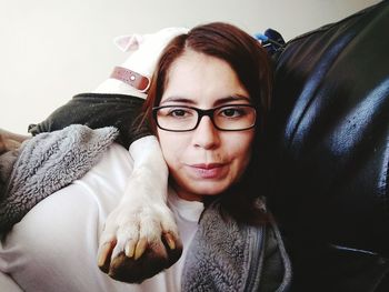 Young woman with dog sitting on chair at home