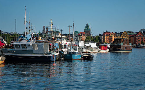 Sailboats moored on sea against sky in city