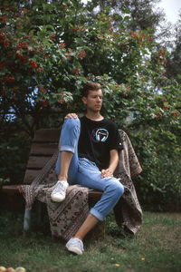 Young woman looking away while sitting on tree