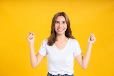 Portrait of a smiling young woman against yellow background