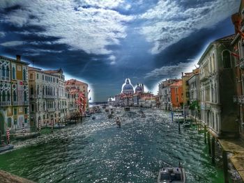 Canal amidst buildings in city against sky