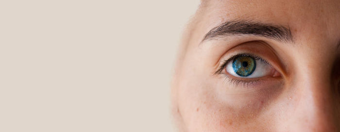 Close-up portrait of human eye against gray background