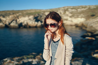 Portrait of young woman wearing sunglasses standing outdoors