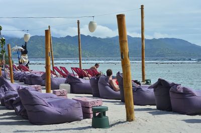 People relaxing at beach against sky