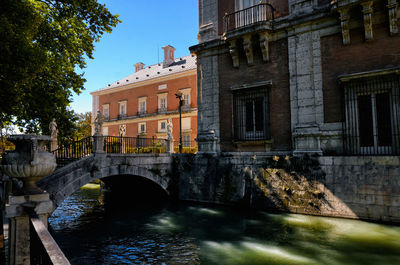 Arch bridge over canal by buildings in city