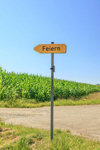 Road sign on field against clear sky